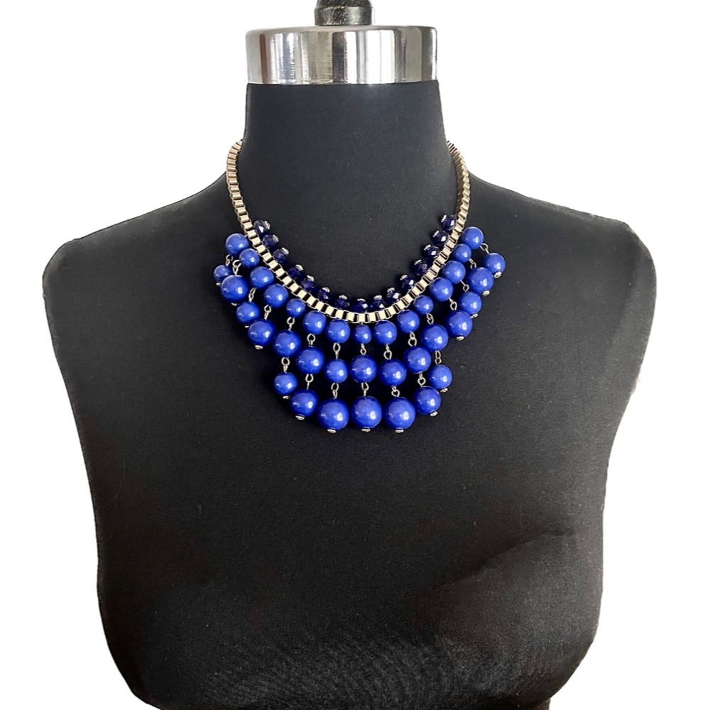 Blue charm style necklace with draped beads and thick gold colored chain.